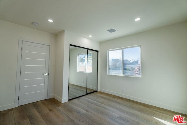 unfurnished bedroom with a closet and light wood-type flooring