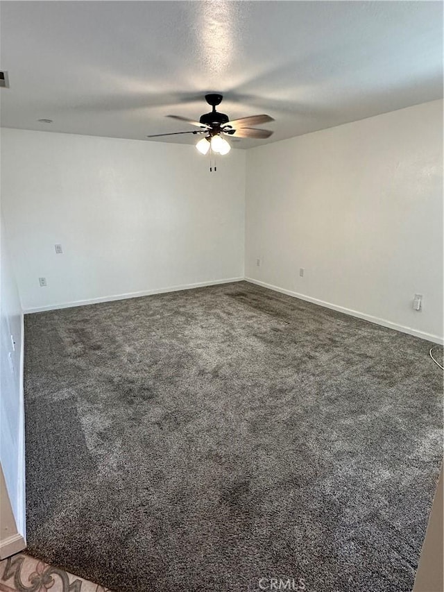 spare room with dark carpet and ceiling fan