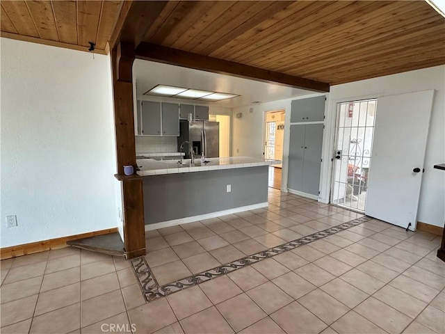 kitchen featuring gray cabinets, light tile patterned flooring, tasteful backsplash, wood ceiling, and stainless steel fridge with ice dispenser