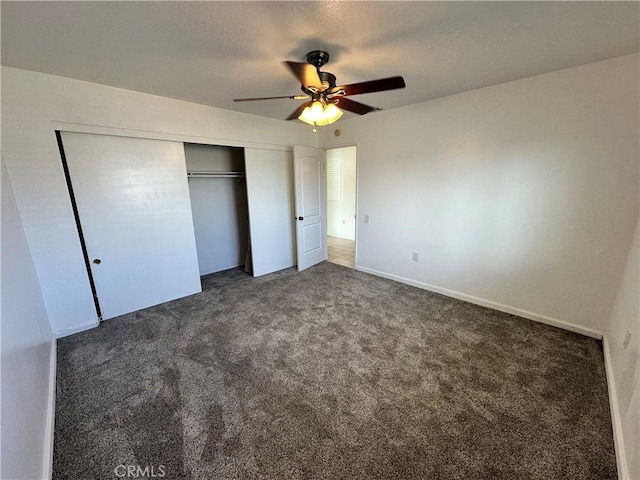 unfurnished bedroom featuring dark colored carpet, ceiling fan, and a closet