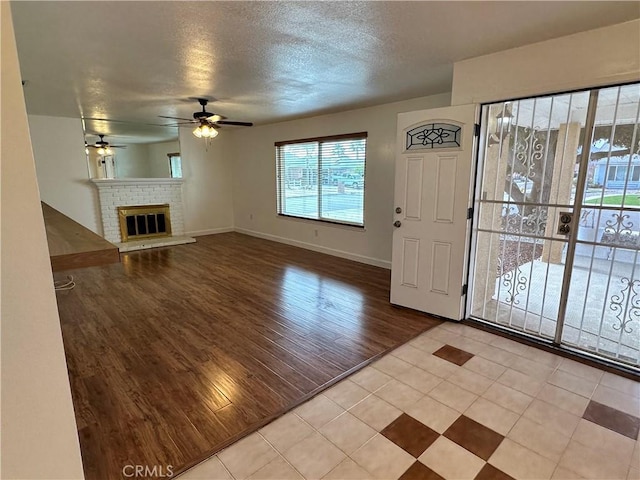 entryway with light hardwood / wood-style flooring, ceiling fan, a fireplace, and a textured ceiling