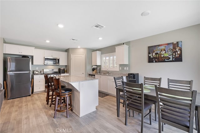 kitchen featuring a kitchen island, appliances with stainless steel finishes, sink, and white cabinets