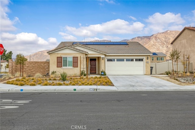 ranch-style house featuring a garage, a mountain view, and solar panels