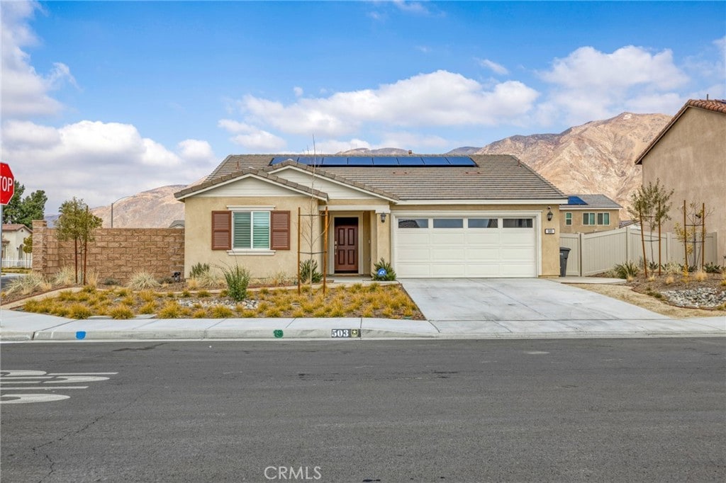 ranch-style home featuring a garage, a mountain view, and solar panels