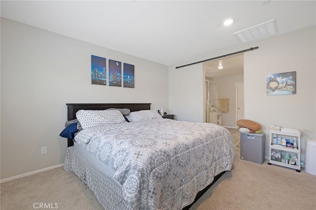 bedroom with light colored carpet and a barn door