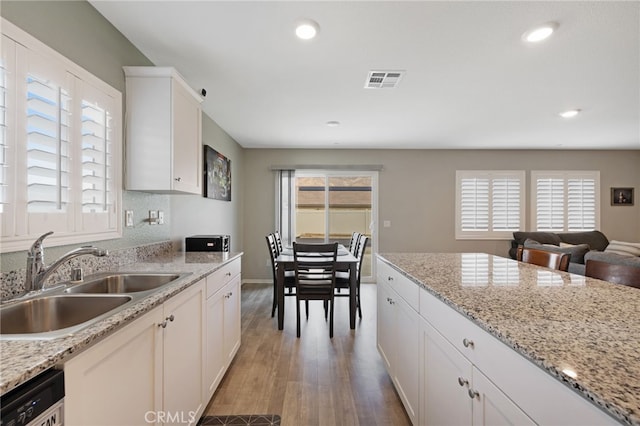 kitchen featuring white cabinetry, dishwasher, sink, light stone countertops, and light hardwood / wood-style flooring