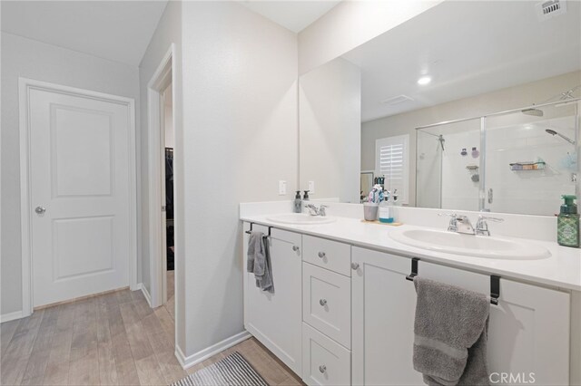 bathroom with hardwood / wood-style flooring, vanity, and an enclosed shower