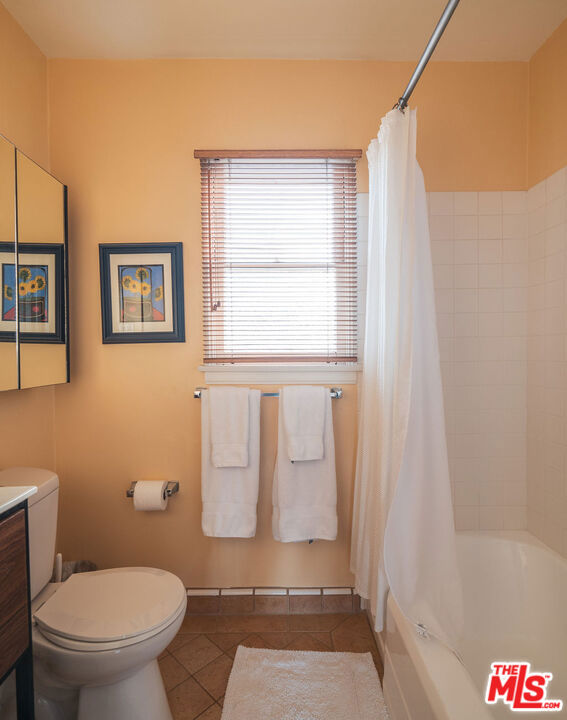 full bathroom featuring shower / bath combination with curtain, vanity, toilet, and tile patterned flooring