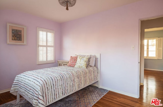 bedroom with multiple windows and dark hardwood / wood-style floors