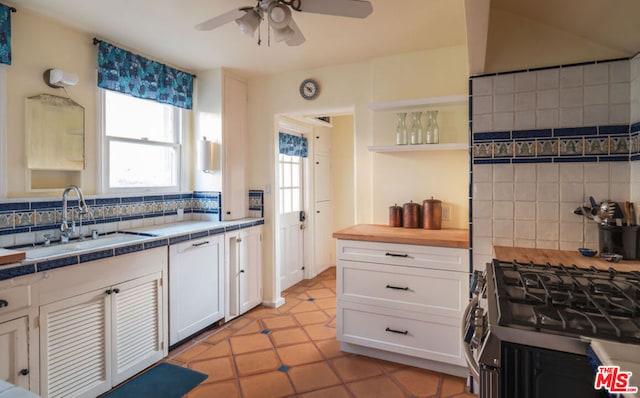 kitchen featuring sink, white dishwasher, tasteful backsplash, tile counters, and white cabinets