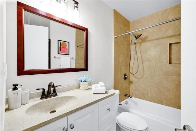 full bathroom featuring tiled shower / bath, vanity, and toilet