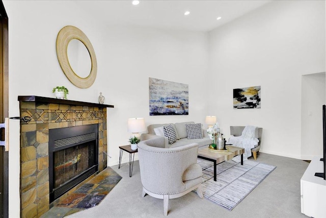 carpeted living room featuring a fireplace and a high ceiling