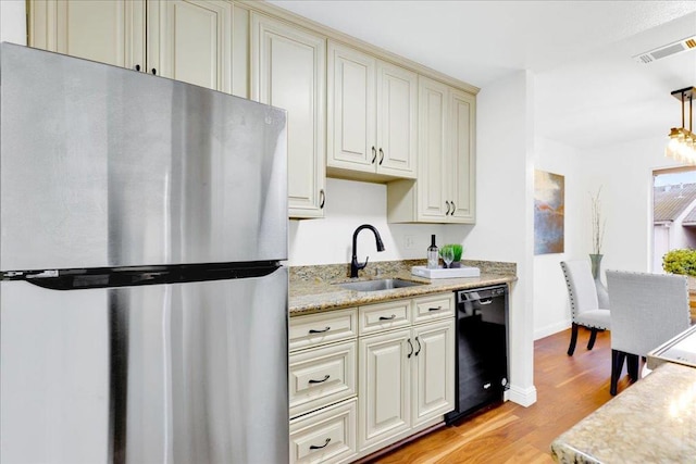 kitchen featuring sink, stainless steel fridge, dishwasher, pendant lighting, and cream cabinets