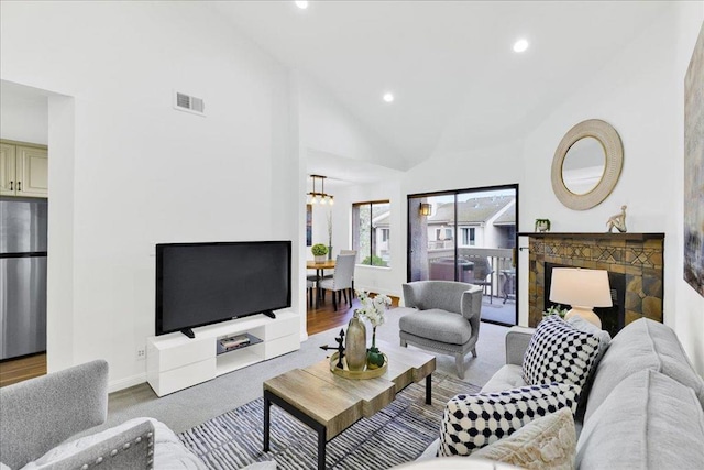 living room featuring a fireplace, high vaulted ceiling, and a notable chandelier