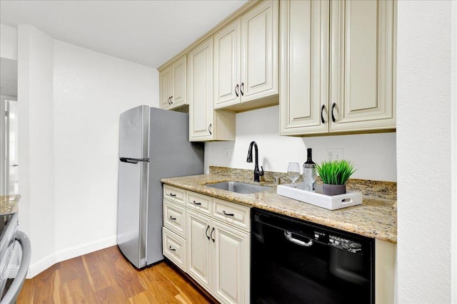 kitchen featuring cream cabinets, stainless steel refrigerator, sink, and black dishwasher