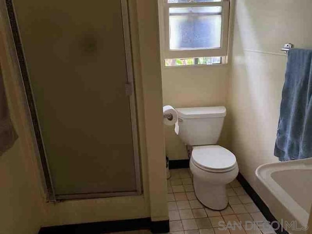 bathroom with tile patterned flooring, a shower with door, and toilet