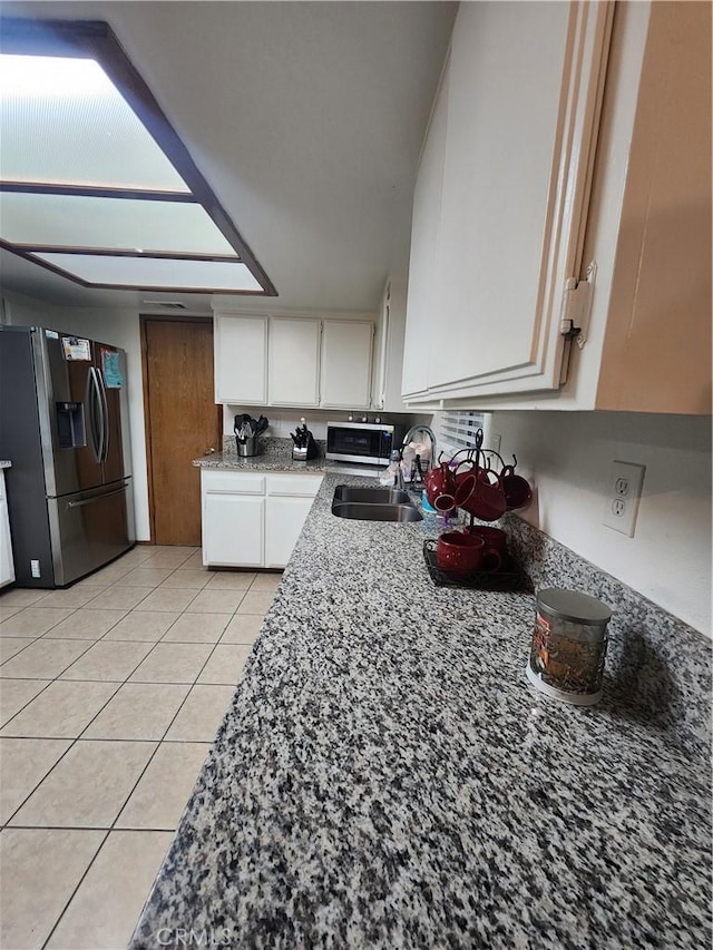 kitchen featuring sink, light stone countertops, stainless steel fridge with ice dispenser, and white cabinets