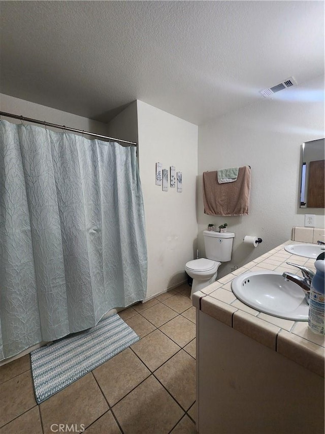 bathroom with vanity, toilet, tile patterned flooring, and a textured ceiling