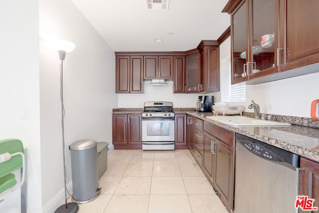 kitchen with light stone countertops, light tile patterned flooring, appliances with stainless steel finishes, and sink