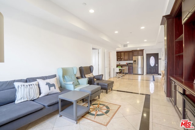 living room with a tray ceiling and light tile patterned floors