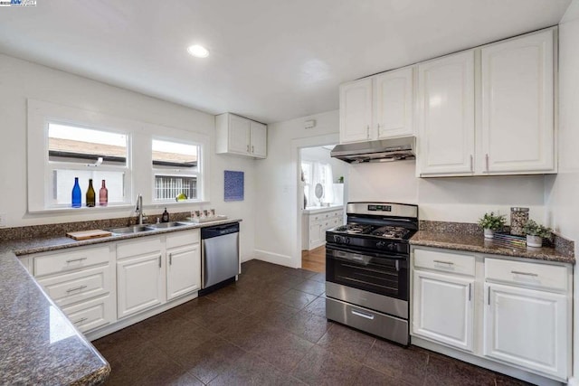 kitchen featuring stainless steel appliances, sink, dark stone counters, and white cabinets