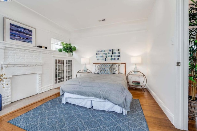 bedroom with wood-type flooring and a fireplace