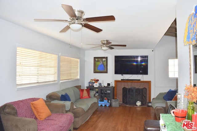 living room featuring wood-type flooring and a brick fireplace