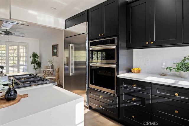 kitchen with appliances with stainless steel finishes, backsplash, and ceiling fan