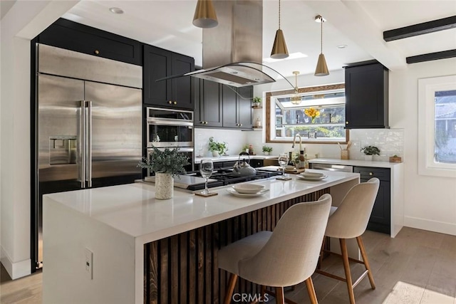 kitchen featuring a kitchen island, pendant lighting, island exhaust hood, stainless steel appliances, and backsplash