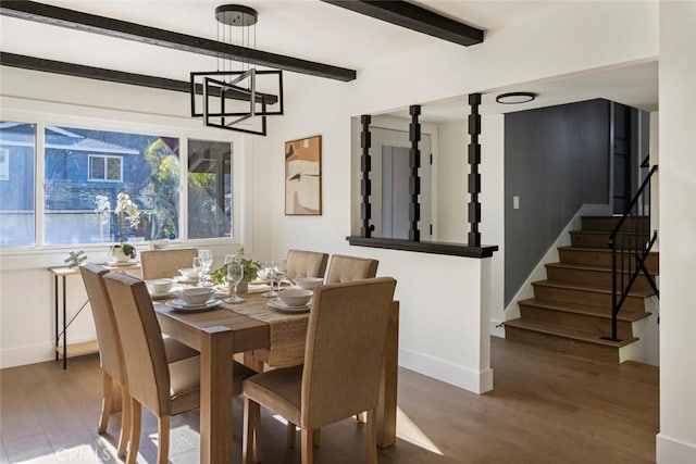 dining area with wood-type flooring, beam ceiling, and a chandelier