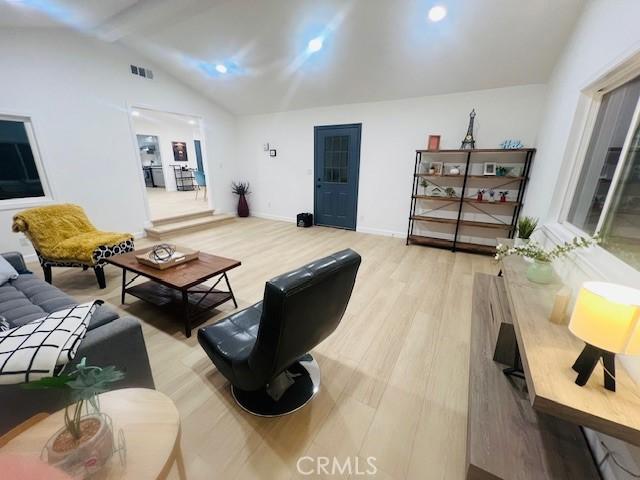 living room featuring light hardwood / wood-style floors and lofted ceiling with beams