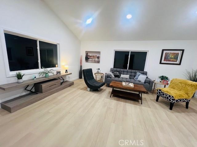 living room featuring high vaulted ceiling and light hardwood / wood-style floors