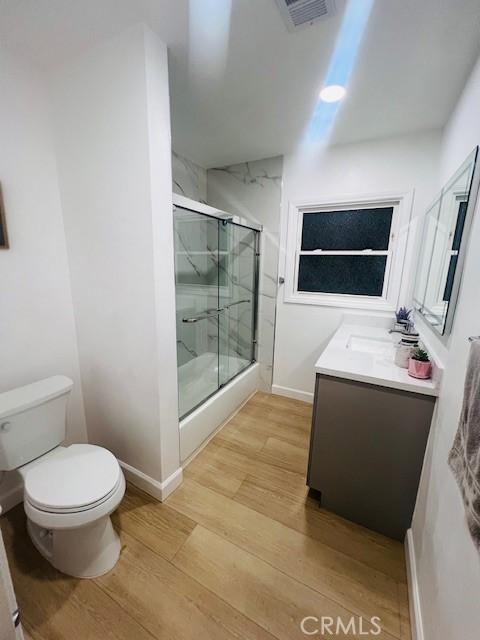 bathroom featuring walk in shower, vanity, toilet, and hardwood / wood-style floors