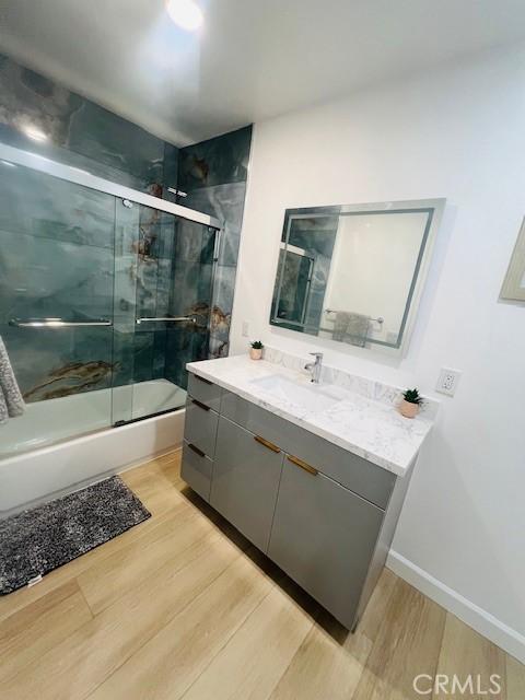 bathroom featuring vanity, hardwood / wood-style flooring, and shower / bath combination with glass door