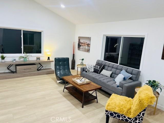 living room with light hardwood / wood-style floors and vaulted ceiling