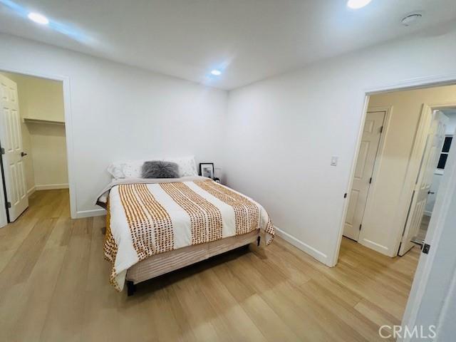 bedroom featuring a walk in closet and light hardwood / wood-style flooring