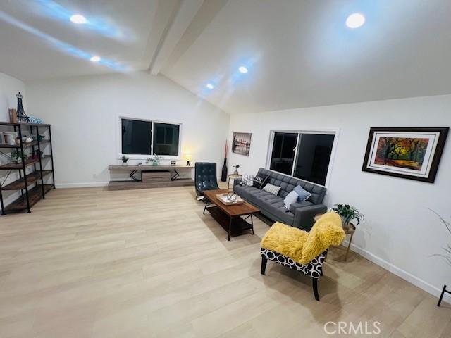 living room with lofted ceiling with beams and light wood-type flooring