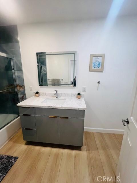 bathroom featuring hardwood / wood-style flooring, vanity, and enclosed tub / shower combo