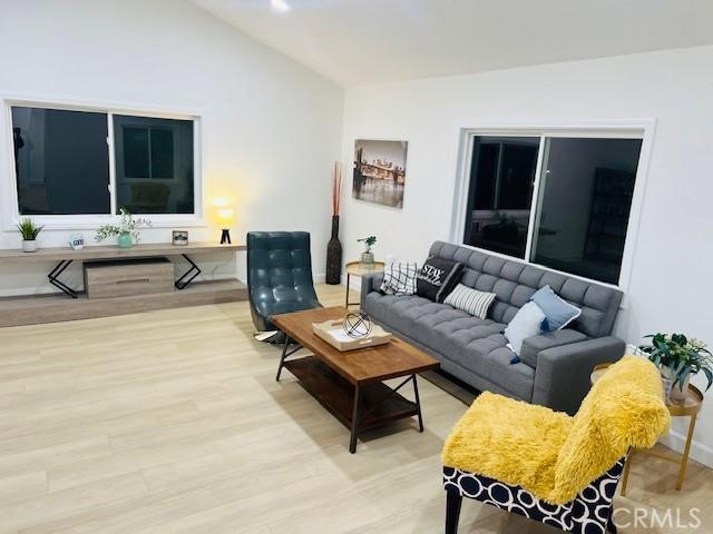 living room featuring lofted ceiling and light hardwood / wood-style floors