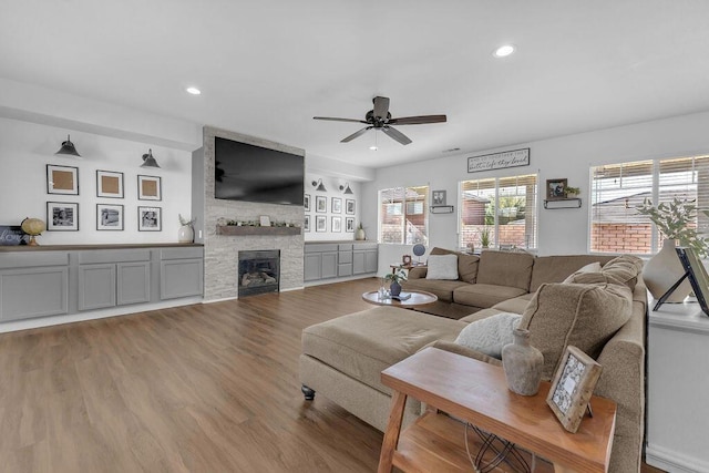 living room with wood-type flooring, a wealth of natural light, ceiling fan, and a fireplace