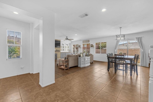 tiled dining area with ceiling fan with notable chandelier