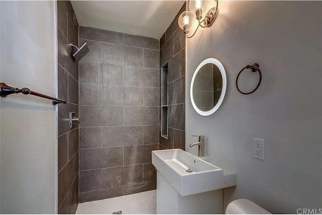 bathroom featuring sink, toilet, and tiled shower