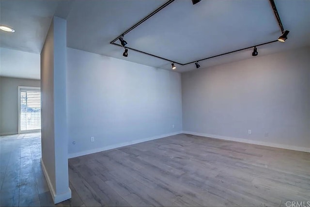 empty room with hardwood / wood-style floors and track lighting