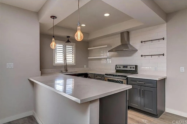 kitchen with wall chimney exhaust hood, kitchen peninsula, stainless steel electric range oven, and hanging light fixtures