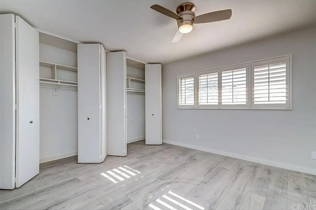 unfurnished bedroom featuring ceiling fan, light hardwood / wood-style flooring, and two closets