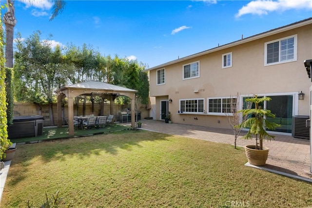 rear view of house featuring a hot tub, a gazebo, a yard, and a patio area