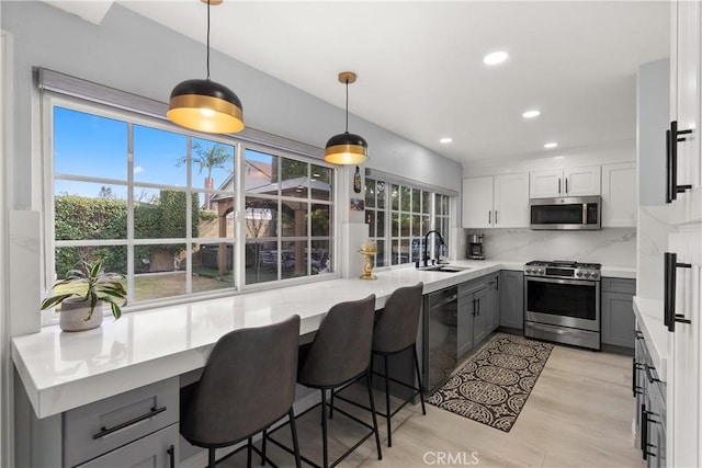 kitchen with gray cabinets, white cabinetry, sink, hanging light fixtures, and stainless steel appliances