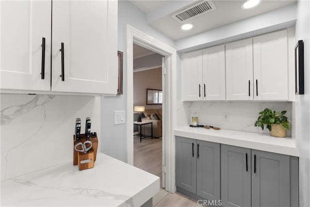 kitchen with gray cabinets, backsplash, white cabinets, and light hardwood / wood-style floors