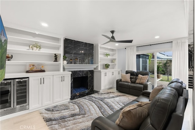 tiled living room featuring a premium fireplace, ceiling fan, wine cooler, built in shelves, and indoor bar