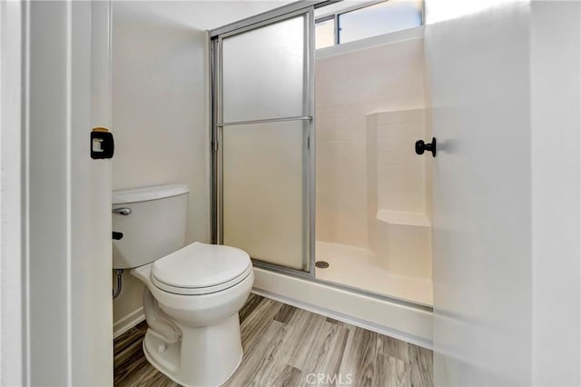 bathroom with hardwood / wood-style flooring, toilet, and a shower with shower door